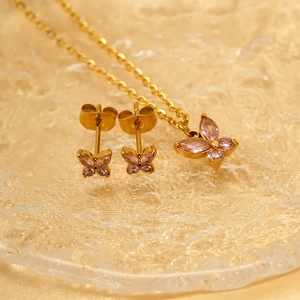 Goldenes Schmetterling Schmuckset mit rosa Steinen, Halskette und Ohrringe auf Glas