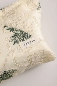 Detail of floral embroidery on off-white linen cosmetic bag with H & R logo label