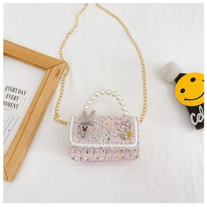 Detail of pink tweed girl's bag with pearl handle, lace trim, and decorative patches