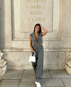 Detailed view of grey sleeveless V-neck vest and matching wide-leg trousers on a model