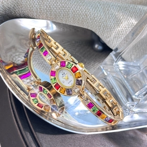 Detailed shot of vintage gold bracelet watch with colorful zircons in a silver tray