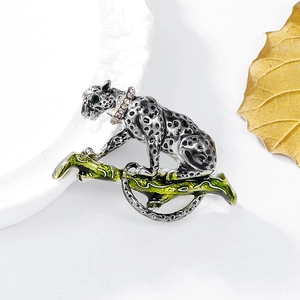 Macro shot of a silver leopard brooch on a green branch with sparkling rhinestones