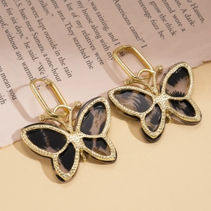 Detail of leopard print acetate butterfly earrings on vintage paper background