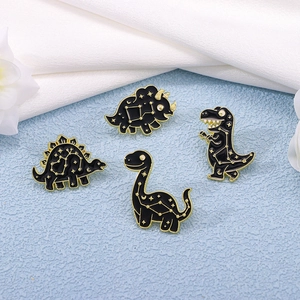 Set of four dinosaur constellation enamel pins in black and gold on light blue background