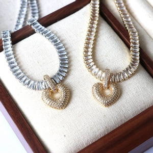 Macro shot of gold and silver heart necklaces with zircon stones on a wooden jewelry box