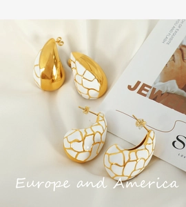 Macro détaillée de boucles d'oreilles rétro françaises en émail or et blanc sur soie
