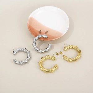 Detail of C-shaped bamboo texture earrings in 18K gold and silver stainless steel finish