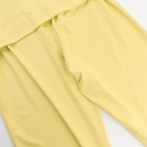 Close-up of light yellow fabric detailing with smooth ruched texture and soft draping