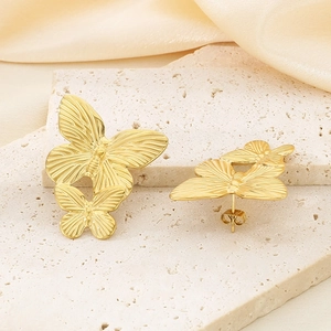 Detailed view of golden butterfly stud earrings with vintage texture on silk fabric