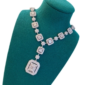 Luxury silver necklace with square and flower links featuring cubic zirconia on a green bust