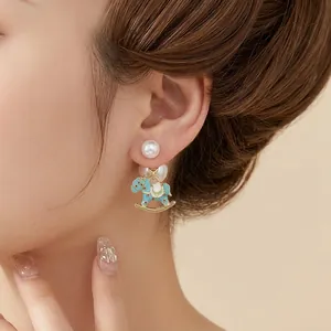 Elegant rocking horse pearl earrings with light blue enamel on a model side view