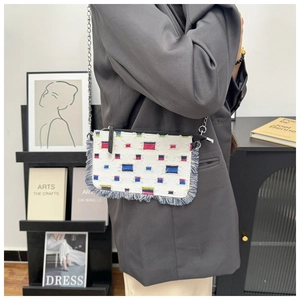Detail of white canvas crossbody bag with colorful patches and blue fringe trim