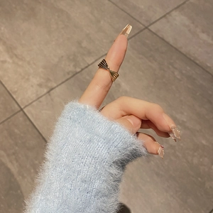 Elegant twisted gold knot ring on finger with light blue sweater and premium texture