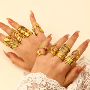 Close-up of bohemian gold rings set featuring floral and wavy designs on model hand