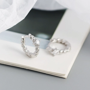 Close-up of twisted silver S925 earrings with square zircon on an elegant background