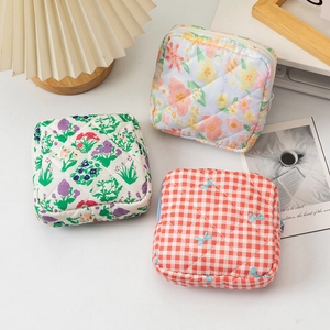 Quilted floral sanitary pouch and makeup bag with smooth zipper detail on white surface