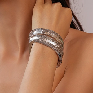 Detail view of a silver wide metal bracelet with textured layered segments on a model wrist
