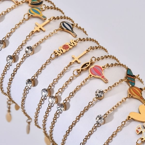 Minimalist gold stainless steel bracelets with cross, heart and MOM charms on a display stand