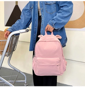 Pink rabbit ears backpack with multiple zipper pockets shown in lifestyle setting
