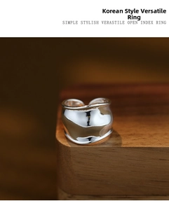 Macro shot of silver wide-band wavy ring with liquid metal texture on a wooden stand