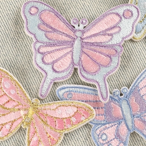 Colorful butterfly embroidery patches in pink and blue on denim fabric background