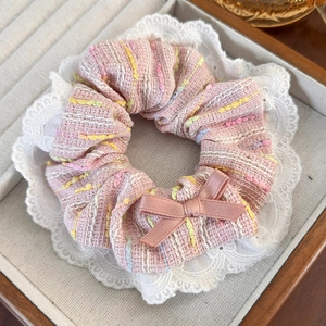 Close-up of pink tweed scrunchie with lace detail and bow on a wooden tray