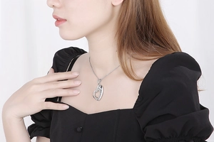 Close-up of a female model wearing a silver hollow heart-shaped stainless steel necklace
