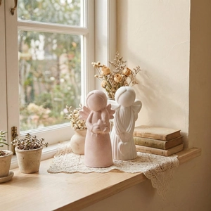 Detail view of pink and white angel statues for home decor in a cottagecore setting