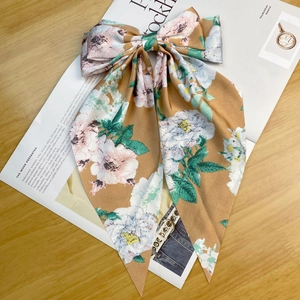 Close-up of vintage brown floral satin ribbon bow hair clip on a magazine