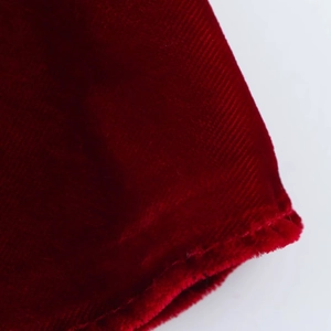 Détail de tissu en velours rouge foncé montrant une texture douce et un fini brillant