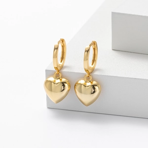 Polished gold heart drop earrings in minimalist style on white geometric stand