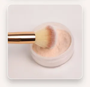 Gros plan d'un pinceau de maquillage double embout prélevant de la poudre libre fine