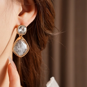 Gros plan de boucles d'oreilles vintage dorées avec faux diamants et quartz rutilé