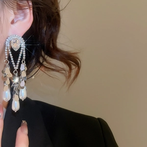 Close-up of silver tassel earrings with sparkling rhinestones and teardrop pearls