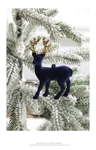 Detail of navy blue flocked reindeer ornament with gold glitter antlers on a snowy tree