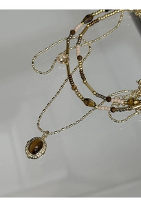 Close-up of gold-plated tiger eye oval pendant with layered bohemian beaded chains