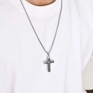Macro shot of silver stainless steel cross pendant and box chain on a male model