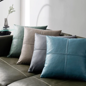 Modern leather texture throw pillow covers in green, beige, grey, and blue on a sofa