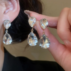 Detailed close-up of crystal teardrop earrings in gold finish worn by a model