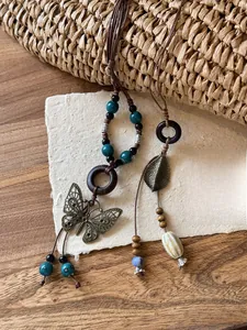 Close-up of bohemian pendant necklace with wooden beads and vintage alloy butterfly leaves