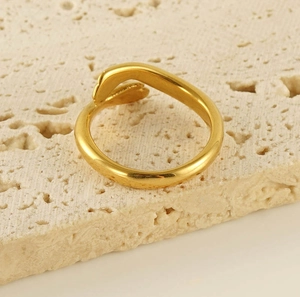 Detail of 18k gold plated stainless steel open ring on a beige textured stone