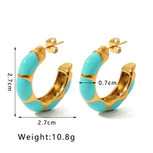 Detail of chunky gold C-shape hoop earrings featuring turquoise blue enamel accents