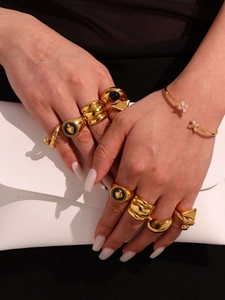 Detail of 18k gold plated agate rings and cuff bracelet worn with a white leather clutch bag