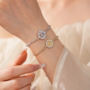 Détail des bracelets avec médailles religieuses incrustées de zircons en or et argent