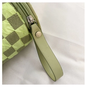 Detail of green checkerboard textured fabric and premium leather handle with metal rivet