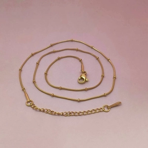 Detail of a minimalist gold satellite chain with small beads and adjustable lobster clasp