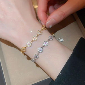 Close-up of gold and silver circular link bracelets with sparkling zircons on a delicate wrist