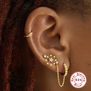 Detailed view of S925 sterling silver gold flower stud and pearl chain ear cuff on model