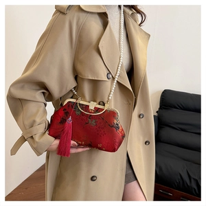 Detailed view of red floral shell bag with pearl chain and tassel on khaki coat