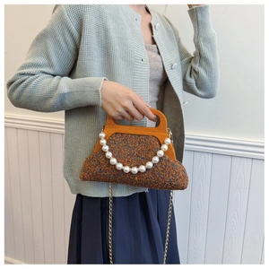 Detail of brown tweed handbag featuring a vintage wooden handle and white pearl chain